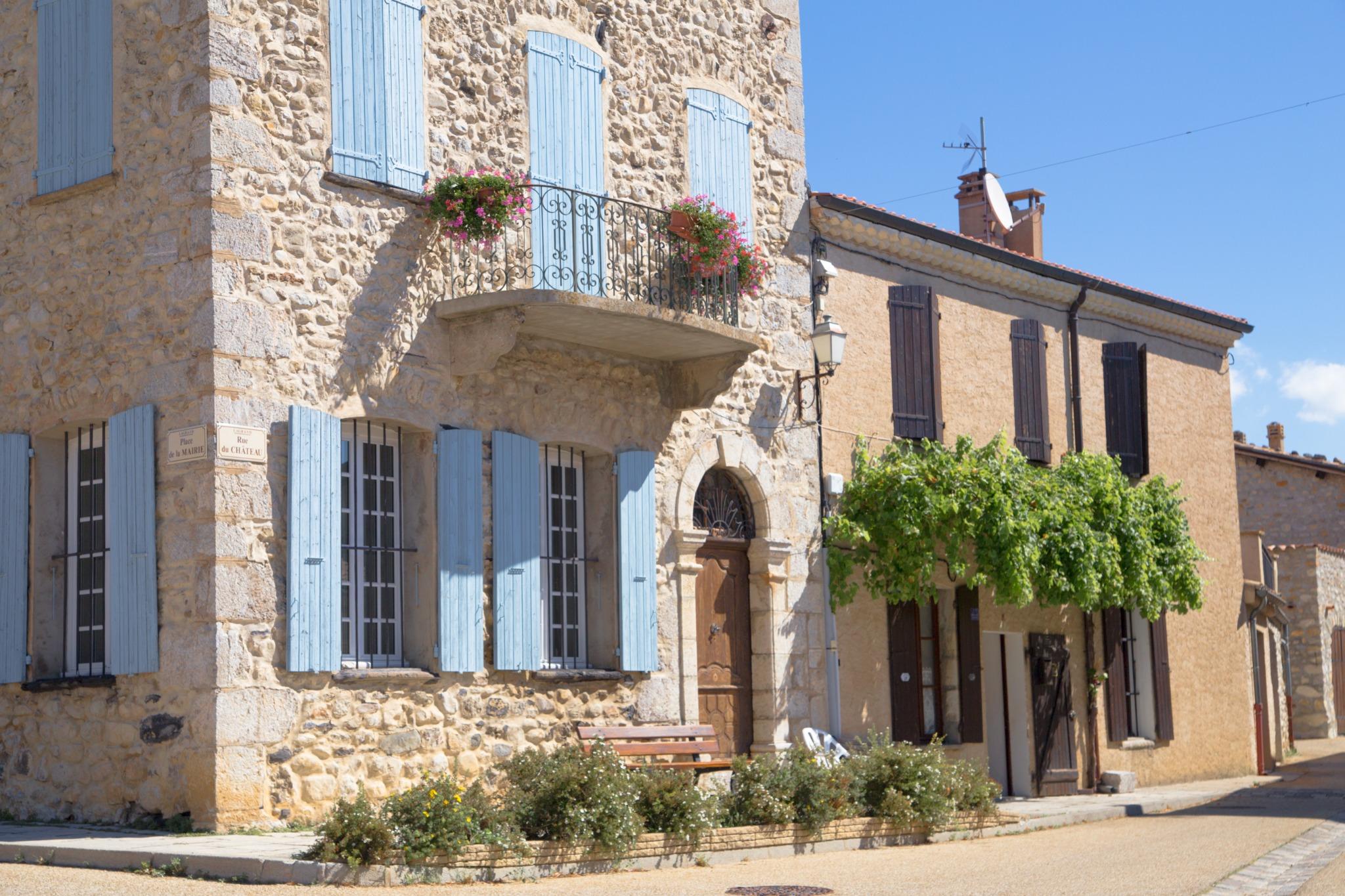 Façade en pierre restaurée avec volets bleus dans un village du sud – architecture traditionnelle